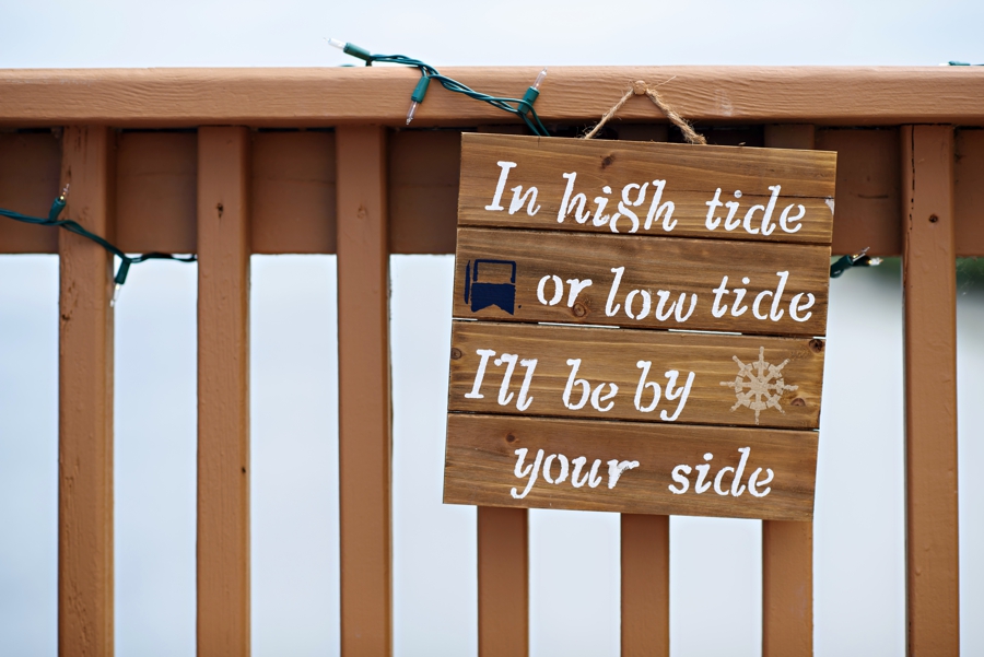A wooden sign that says In high tide or low tide I'll be by your side.